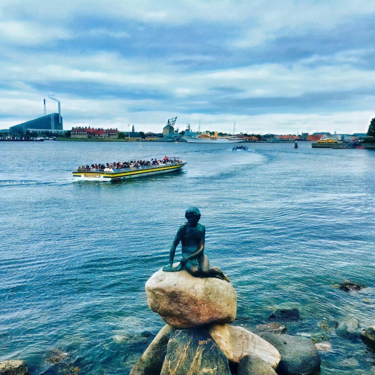 man in black jacket sitting on rock near body of water during daytime